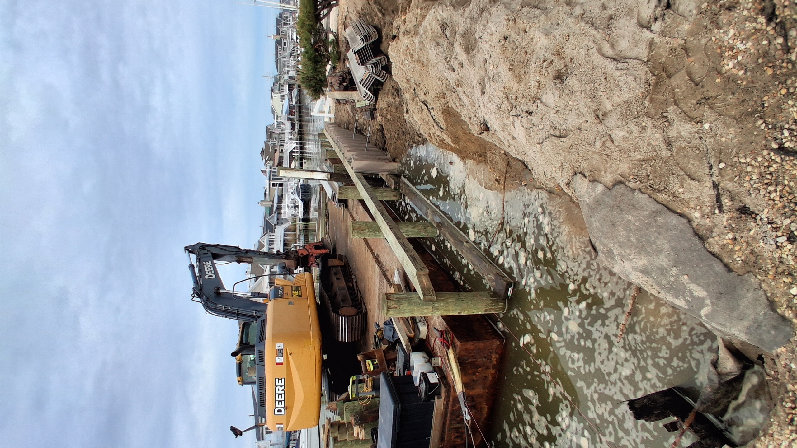Deere excavator on barge driving steel sheet pile